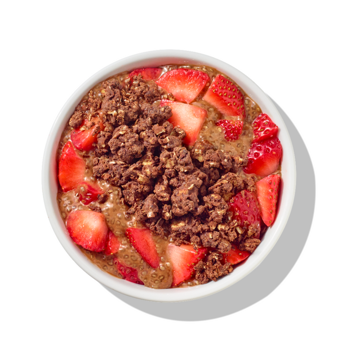 A top-down view of a white bowl filled with granola. chocolate chia pudding, fresh sliced strawberries on a white background with a soft shadow.