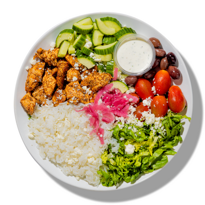 Plated dish with chicken, rice, vegetables, and a side of sauce on a white background
