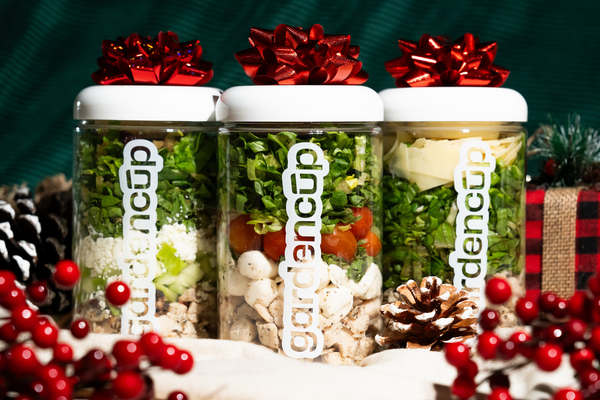 Three jars with garden cup branding, decorated with red bows and Christmas elements on a green background.