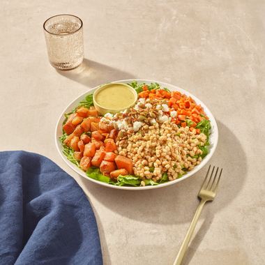 Roasted Veggies + Farro plated in a bowl with honey lemon Dijon dressing, ready to eat.